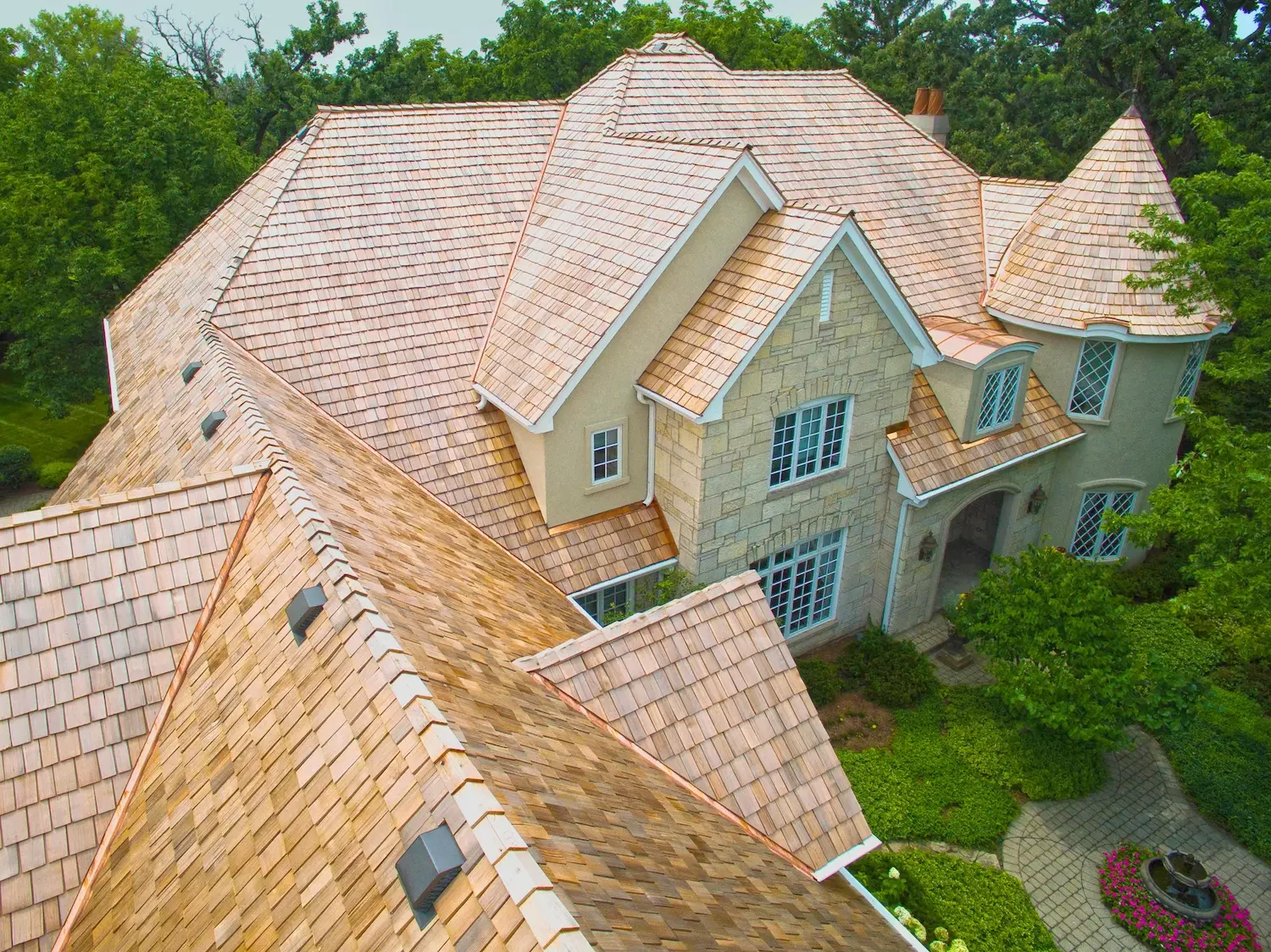 Aerial view of a stunning new cedar shake roof with copper flashing on a luxury estate.