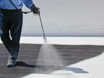 Close-up of spray gun applying waterproof roof coating to create a seamless membrane
