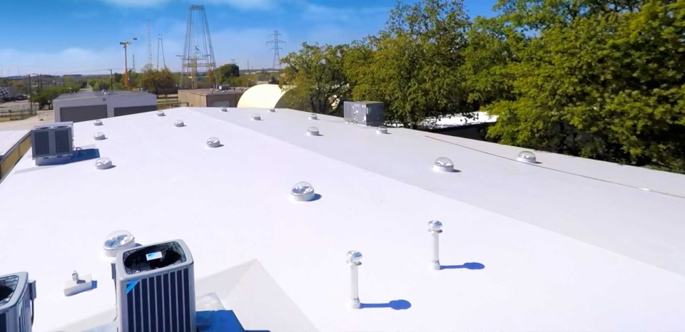 A clean TPO roof installation around various rooftop HVAC units and vents.