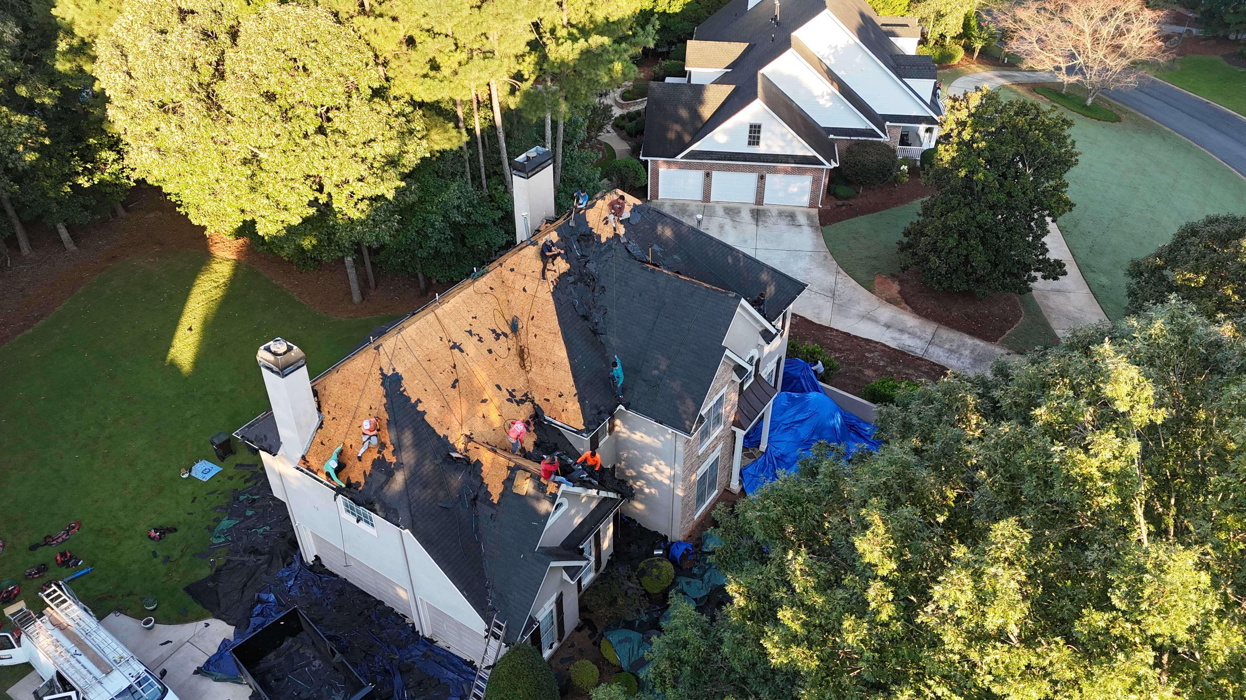 Aerial view of Summit Roofing crew actively replacing storm-damaged roof with new shingles during insurance claim work
