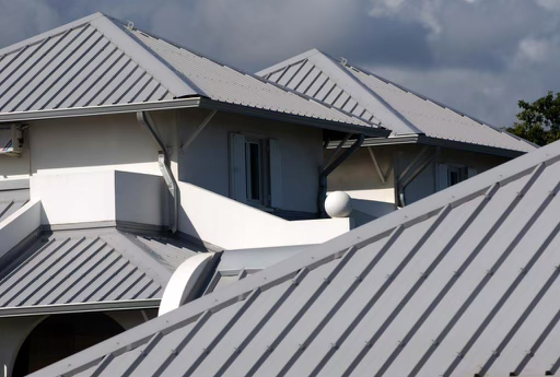 Clean lines of a light-colored standing seam metal roof on a modern building.