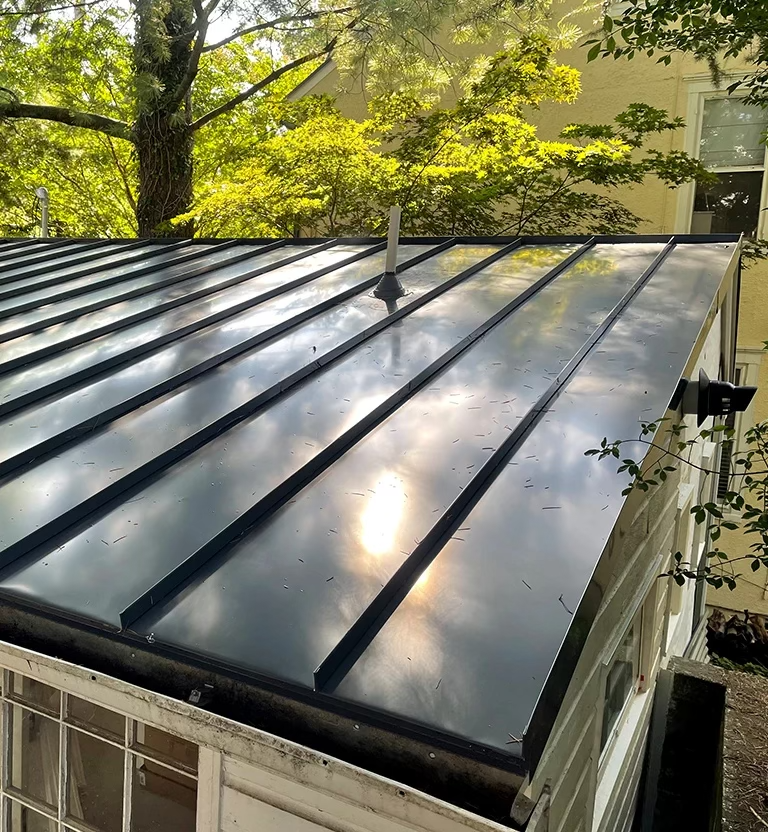 Glossy standing seam metal roof reflecting the sun on a home extension.