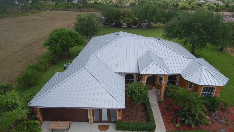 Light-colored standing seam metal roof on a large residential property.