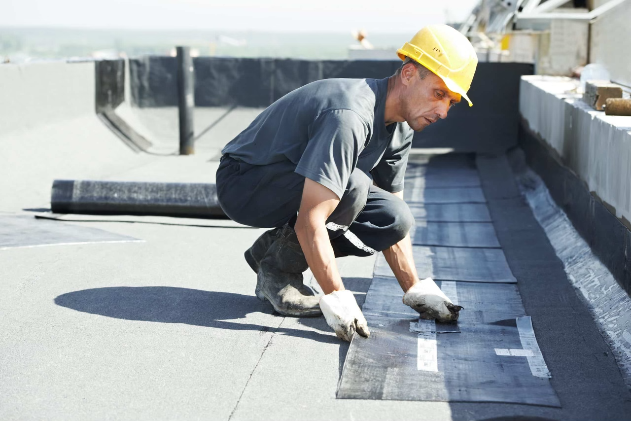 Professional roofer carefully applying a patch to a flat roof.
