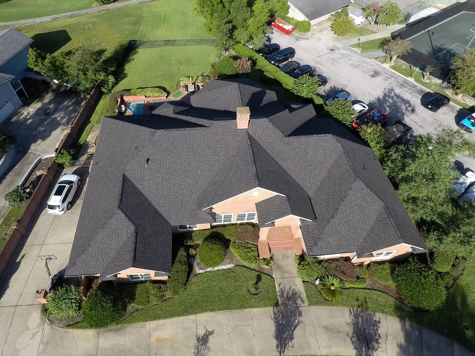 Aerial view of a complete architectural shingle roof replacement on a large brick home.
