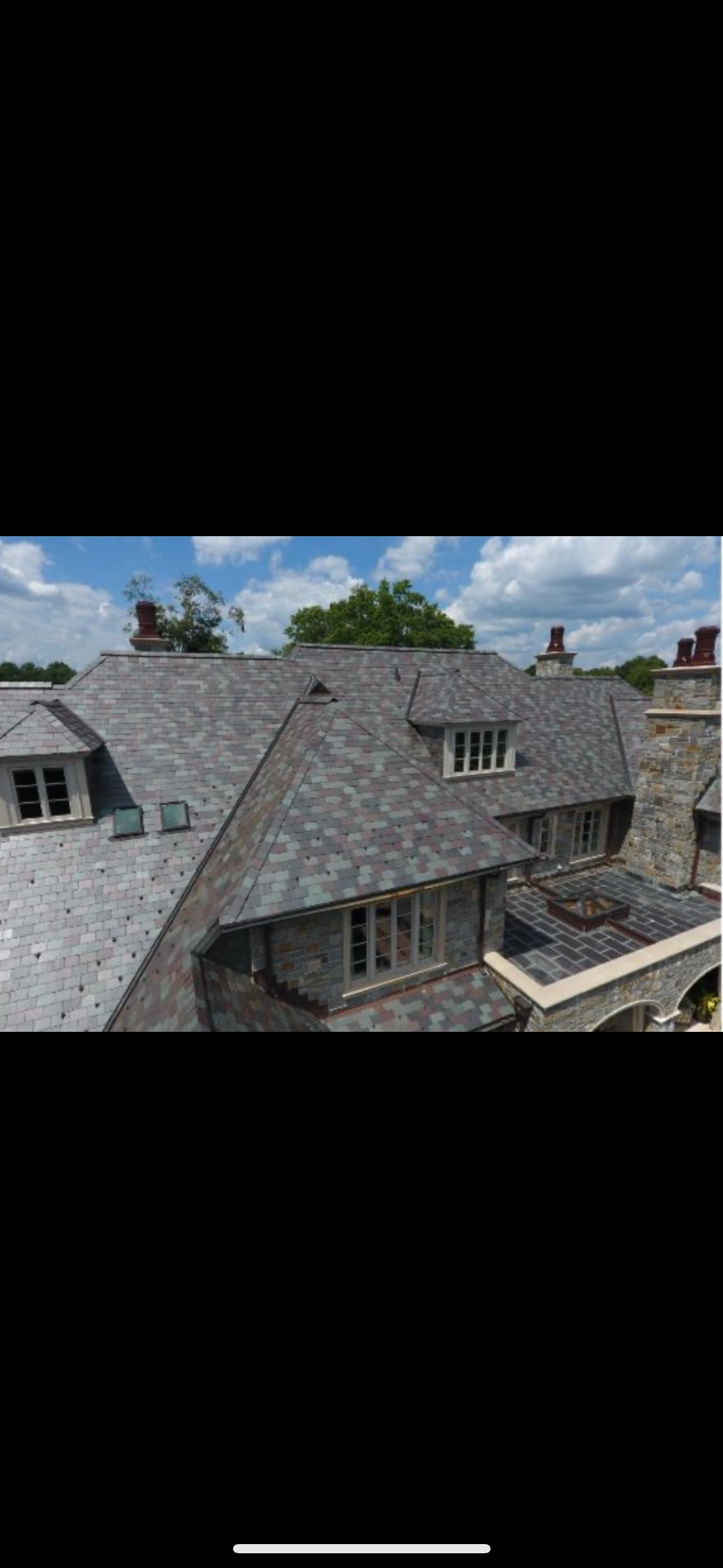 Multi-colored slate roof on a grand estate, showcasing a blend of grey, green, and red tiles.