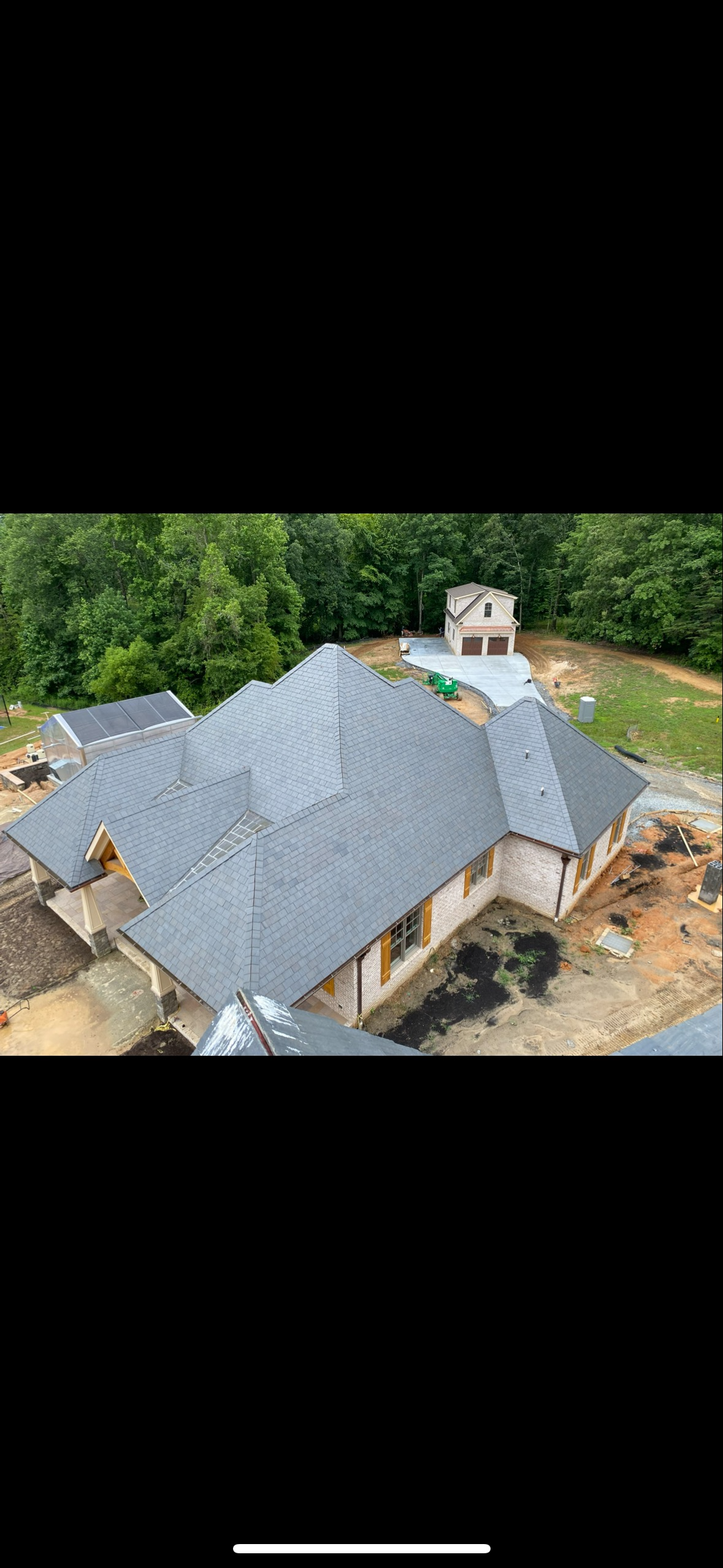 Pristine grey slate roof installation on a new construction home with light brick exterior.