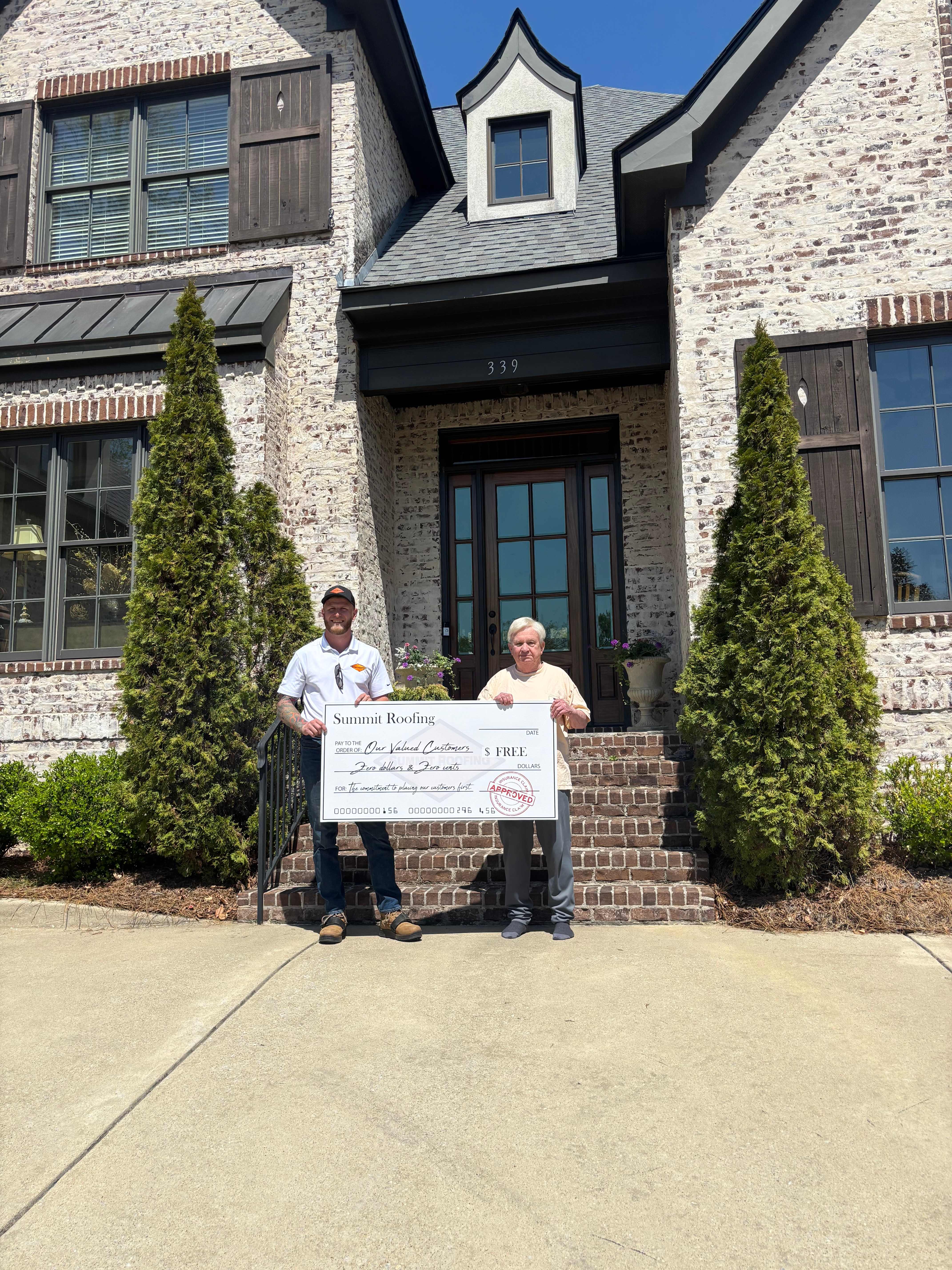 Customer Bill P. with a Summit Roofing representative in front of his new roof.